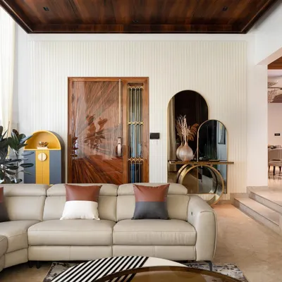 The entrance to the penthouse features a 9-foot veneer door that opens into the voluminous living space. I used a custom brass console table with tinted mirrors against a white grooved panel wall to create a welcoming and luxurious first impression.