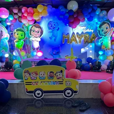 A complete stage setup for a Cocomelon first birthday party. I filled the stage with colorful balloon garlands and life-sized cutouts of JJ and his friends, with the iconic yellow school bus right at the front.