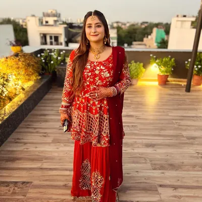A beautiful bride-to-be at her pre-wedding function. She is wearing a surreal burnt orange and maroon gharara with a peplum top, all hand-embroidered with finesse.