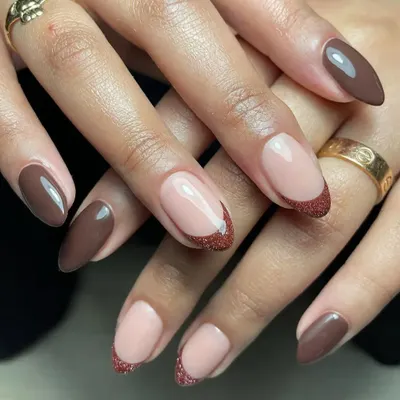 A chic and earthy design combining solid brown nails with a glittery brown French tip on an almond shape.