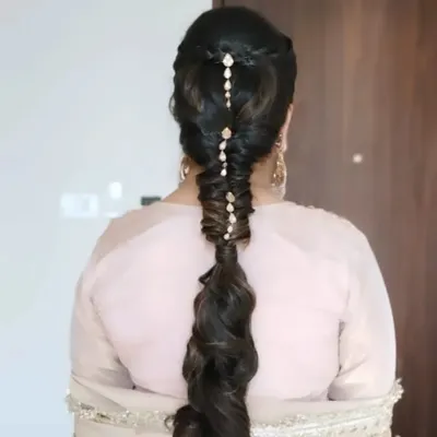 A stunning and intricate pull-through braid, decorated with delicate hair jewelry. This is a modern and stylish choice for a Mehendi or Sangeet event.
