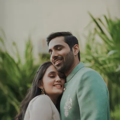 A heartfelt portrait of a couple embracing, their eyes closed in a moment of pure comfort and happiness. The lush green background adds to the natural, candid feel of this engagement photo.
