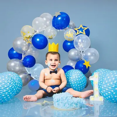 A classic cake smash for a first birthday! This little prince is having the best time with his blue-themed setup, complete with a crown and a delicious cake.