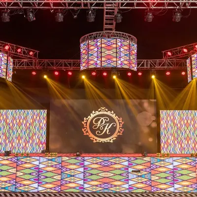 A massive, fully-equipped Sangeet stage with multiple LED screens and a complex lighting rig. I design stages like this to provide a versatile and dynamic backdrop for a variety of performances, complete with custom monograms.