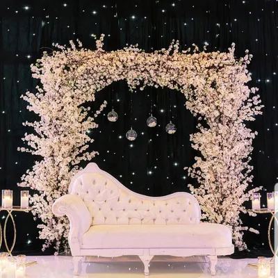 This engagement ceremony photobooth features a stunning arch of white cherry blossoms against a starry black backdrop. The elegant chaise lounge provides the perfect spot for beautiful, timeless photos.