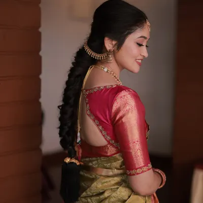 A detailed view of a classic South Indian bridal braid. This hairstyle is neat and elegant, adorned with a traditional earpiece chain (matti) for a complete look.