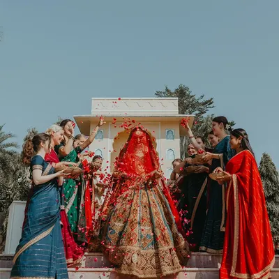 The bride's grand entrance at a beautiful Rajasthan wedding, showered with petals by her bridesmaids. This is a moment of pure celebration and anticipation.