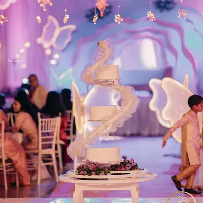 A stunning multi-tiered wedding cake with a unique spiral design, set against a whimsical, butterfly-themed backdrop.