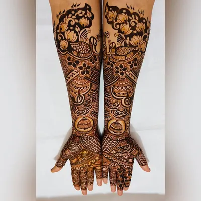 This engagement mehendi showcases a blend of traditional motifs. It features proud peacocks and blooming gulf flowers, creating a full and festive design that extends up the forearm.