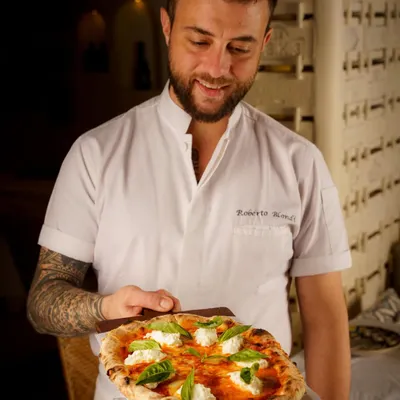 A proud chef presenting his creation. This shot for Bizza Mumbai connects the food to the person who made it, adding a layer of authenticity and passion. The Neapolitan style pizza looks fresh and delicious.