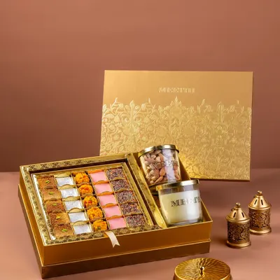 A festive gift box for Meethi India, featuring an assortment of Indian sweets, a scented candle, and dry fruits. The styling is elegant and targeted towards the luxury gifting market.