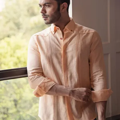 Invest in quality, feel the difference. This peach linen shirt, with its subtle pintuck details, is made from the finest materials for lasting comfort and style on warm days.