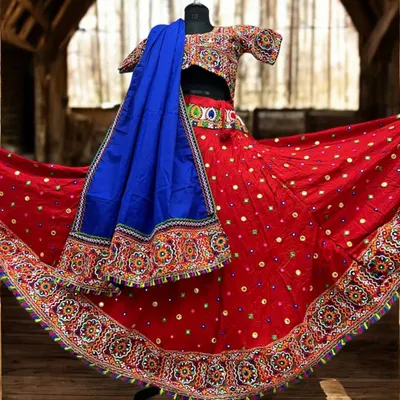 This classic red dandiya lehenga is a showstopper. The skirt and blouse are covered in traditional Kutchi embroidery and mirror work, paired with a contrasting royal blue dupatta for a truly vibrant look.