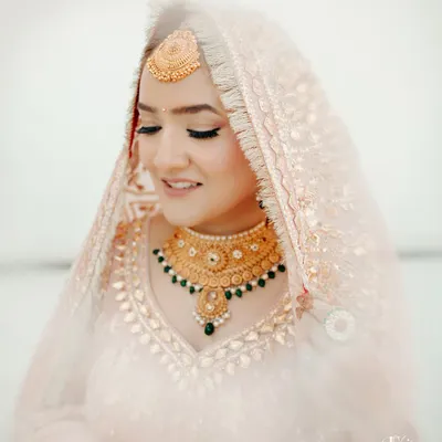 A soft and delicate portrait of a Sikh bride, her eyes gently closed, highlighting her beautiful makeup and traditional gold jewelry.