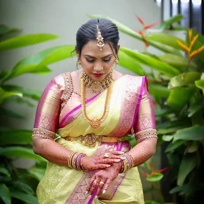 A bride in a moment of quiet reflection, wearing a traditional Kanjeevaram saree with a custom-designed pink and gold embroidered blouse.