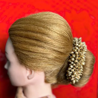 A side profile of a classic bridal bun adorned with a gajra of golden buds. In my course, you will learn how to create a smooth, perfectly rounded shape and secure heavy accessories.