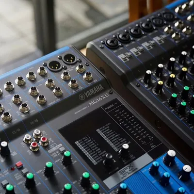 A close-up of the Yamaha MG16XU audio mixer. This shot highlights the high-quality D-PRE mic preamps and rugged metal chassis, built for reliable performance in the studio or on the road.