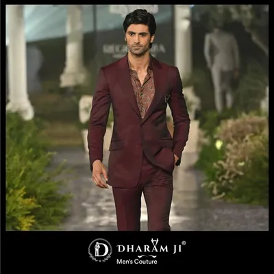 A model on the runway in a deep maroon suit. The slim fit and rich color make it a sophisticated choice for a wedding reception or formal dinner.