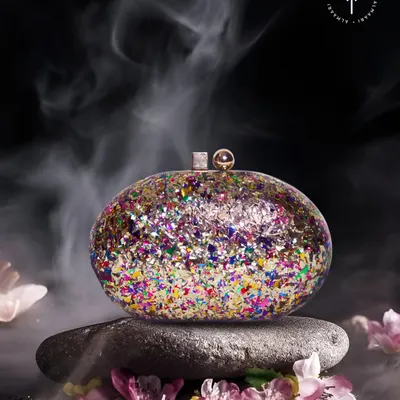 This clutch is a party in your hand. A hard-shell oval clutch filled with multi-colored glitter is the perfect fun accessory for a sangeet, cocktail night, or any celebration.