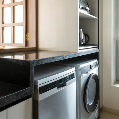 Integrating laundry into the kitchen is a smart solution for modern Indian homes. Here, the dishwasher and washing machine sit side-by-side under the counter, making the kitchen a highly efficient hub for all household chores.