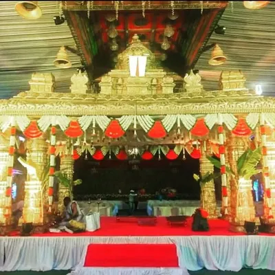 This 'Tirupati' style mandap is designed to replicate the grandeur of a temple, with ornate pillars, a detailed roof structure, and traditional bell hangings for an authentic ceremonial feel.