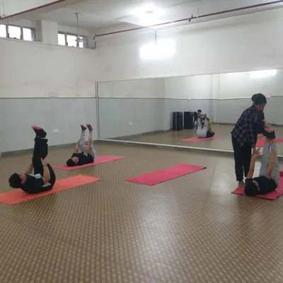 An instructor provides personal assistance to a student during a yoga class in our mirrored studio. We keep our batches small to ensure everyone gets the guidance they need to improve their posture and flexibility.