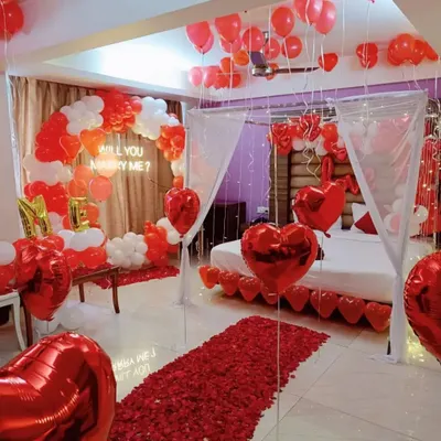 This is a complete proposal setup I designed for a client's room. It includes a 'Will you marry me?' neon sign, a red and white balloon arch, a rose petal walkway, and a decorated bed under a light-up canopy.