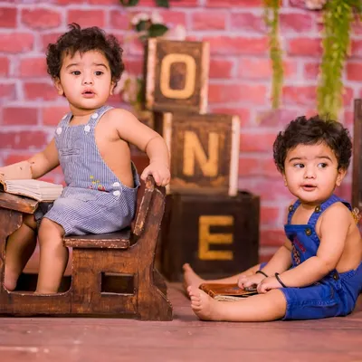 Our rustic schoolhouse set is a fantastic choice for twins. It's spacious enough for two and comes with props like a mini school desk, chalkboard, and "ONE" blocks for a charming first birthday shoot.
