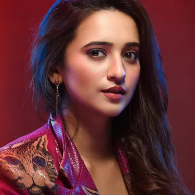 This portrait combines fashion with a cinematic mood. The red background and subtle blue highlights create a vibrant color palette, while the model's direct gaze makes for a confident and engaging shot, perfect for an actor's lookbook.
