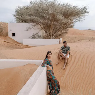 A destination pre-wedding shoot in the stunning Dubai desert. The unique architecture half-buried in sand creates a surreal and beautiful setting for this couple's portrait, showcasing how exotic locations can elevate a photoshoot.