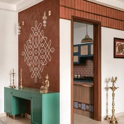 Every story begins at the threshold. This foyer from "The Varnam Edit" welcomes guests with a hand-drawn kolam on a terracotta-textured wall, a traditional South Indian invocation of grace.