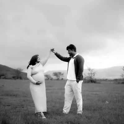 A timeless black and white photograph of a couple sharing a dance in an open field. This image captures the romance and joy of their journey together as they await their new arrival.