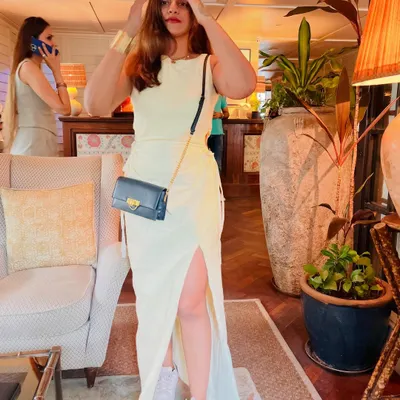 A full-length shot of this pale yellow dress with a side slit, paired with white sneakers for a casual, comfortable vibe. This is a great example of how to style a dress for a relaxed day out.