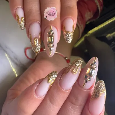 A close-up of our special Karwachauth nails. This design features a neutral base with dripping gold glitter, 3D gold accents, and large gemstone embellishments for a truly festive look.