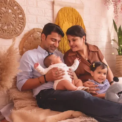 A candid moment during a family photoshoot, with parents and their two children sharing a smile. We set up this cozy boho-style scene to make everyone feel comfortable and capture genuine interactions.