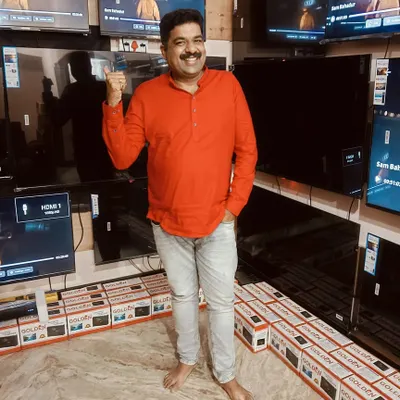 At my friend's Golden TV shop in Nagarabhavi, surrounded by the latest models. I was there to help promote his business. It's a great feeling to support a friend's venture.