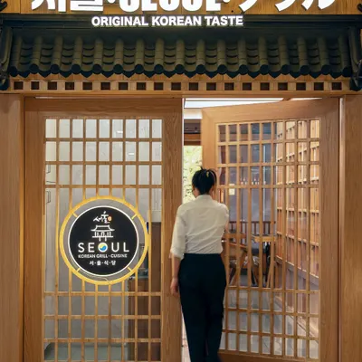 The entrance to Seoul was designed to be a cultural gateway. The traditional wooden lattice doors and signage in multiple scripts immediately signal a space dedicated to authentic Korean taste, setting a narrative tone from the very first step.