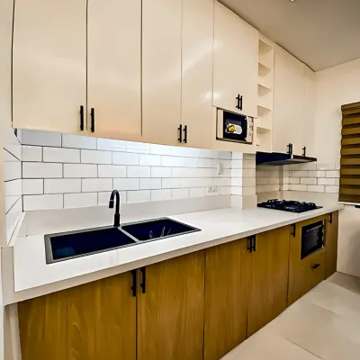 A sleek parallel kitchen combining natural wood grain on the lower cabinets with clean white overhead storage. This design maximizes a narrow space, offering ample counter area and a modern look with its white subway tile backsplash.