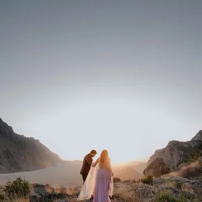 A breathtaking sunset shoot in the mountains. This image is all about the scale of nature and the intimacy of the couple within it. The groom helping his partner with her dress is a small, beautiful gesture of love.