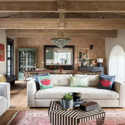 In this Saratoga home near San Francisco, we infused a traditional American interior with Indian soul. The living room features a comfortable, modern sofa paired with a bold, striped coffee table and a vintage-style rug. The wood-beamed ceiling adds rustic warmth, creating a space that feels both worldly and homely.