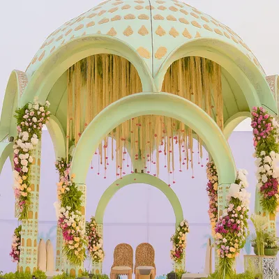 A close-up of our Sheesh Mahal-inspired mandap, showcasing the pastel green dome with intricate gold-leaf patterns. This structure was designed to feel grand yet delicate, creating a fairytale setting for the vows.