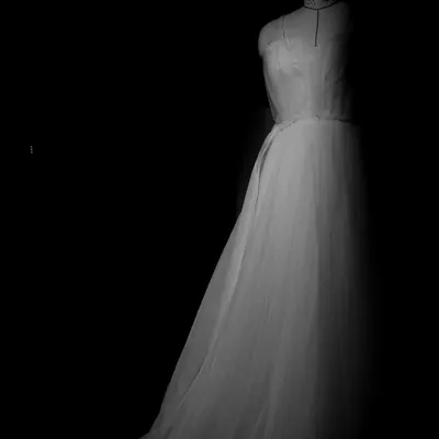 A sneak peek of a white bridal gown in the making, seen here on my mannequin. This image captures a quiet moment in the creation process, showing the gown's silhouette and the delicate tulle fabric before the final details are added.