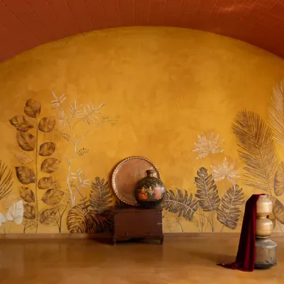 This curved feature wall is finished in yellow oxide with leaf imprints, created in collaboration with an artist. The wall becomes a canvas, bringing the texture and patterns of the outdoor landscape into the living space.