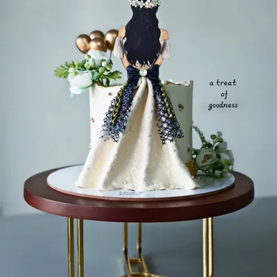 A chic and elegant cake for a bride-to-be. The design features a hand-piped dress illustration on a simple white buttercream cake, creating a beautiful and personal statement piece.