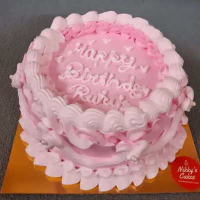 A classic birthday cake with a simple and pretty design. This cake features pink and white whipped cream frosting piped in a delicate, frilly pattern, perfect for an intimate and sweet celebration.