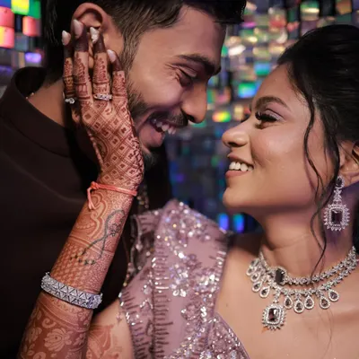 A beautiful, intimate moment between the couple at their sangeet. The bride's makeup is glowing, with a focus on her intricate henna and stunning diamond jewellery.