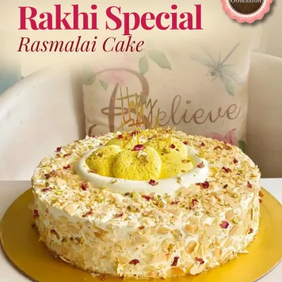 A delicious Rakhi Special Rasmalai Cake, generously garnished with nuts and rose petals, perfect for the festive occasion.