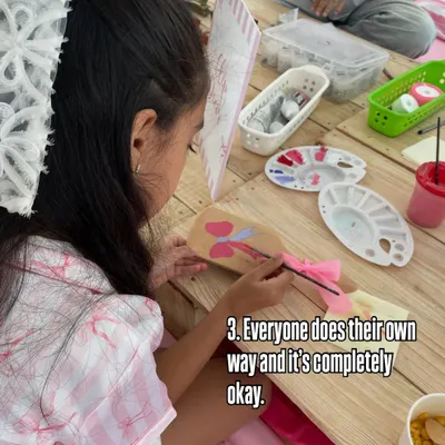 One of the beautiful things I observe is that every child does it their own way, and it's completely okay. This young girl is carefully painting a wooden paddle with her unique design.