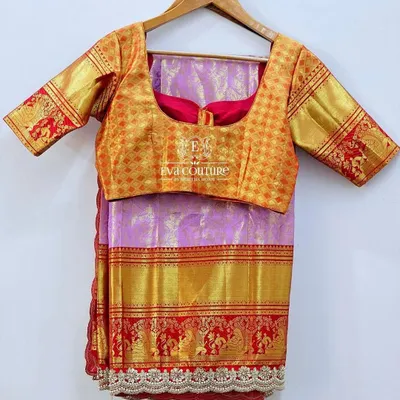 A beautiful Kanchi Pattu saree in lilac with a red and gold border. It is paired with a contrasting gold brocade blouse for a classic and elegant look.