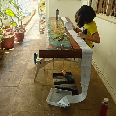A child works on a long timeline, gluing paper upon paper to map out vast stretches of history. This kind of "big work" allows her to physically grasp the scale of time and connect different historical events in a meaningful way.